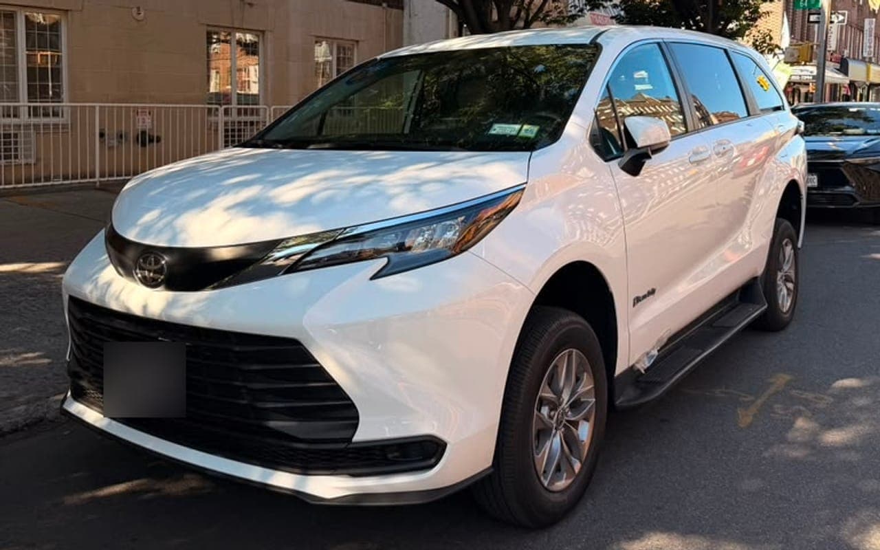 A white wheelchair accessible Toyota Sienna parked on a sunny street, seen from the front