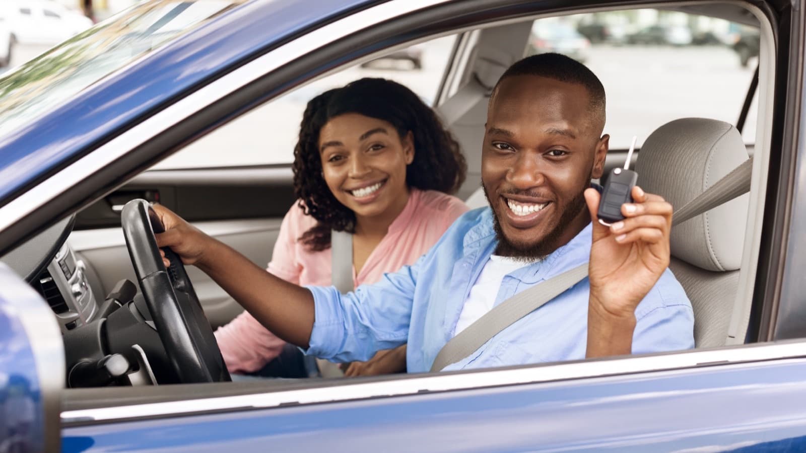 A happy couple in their new car holding the keys