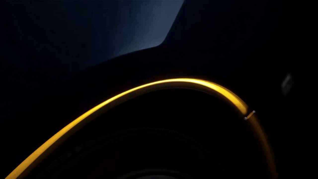 An amber light tracing the wheel arch of a dark car