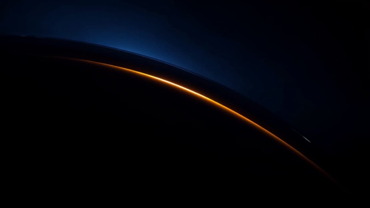 A raking amber light revealing the surface of a dark car panel