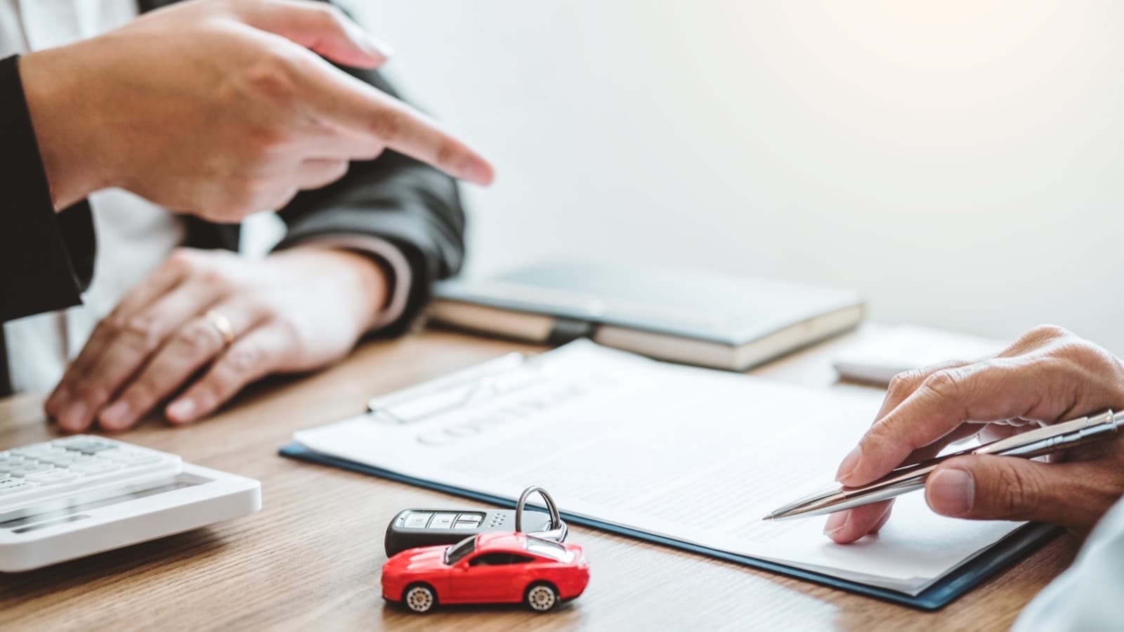 A lease agreement being signed with car keys on the desk