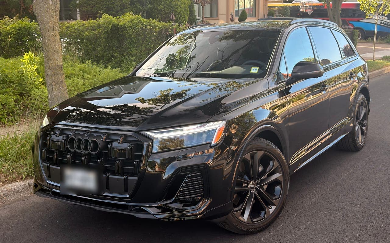 A black Audi Q7 with blacked out trim on a tree lined street