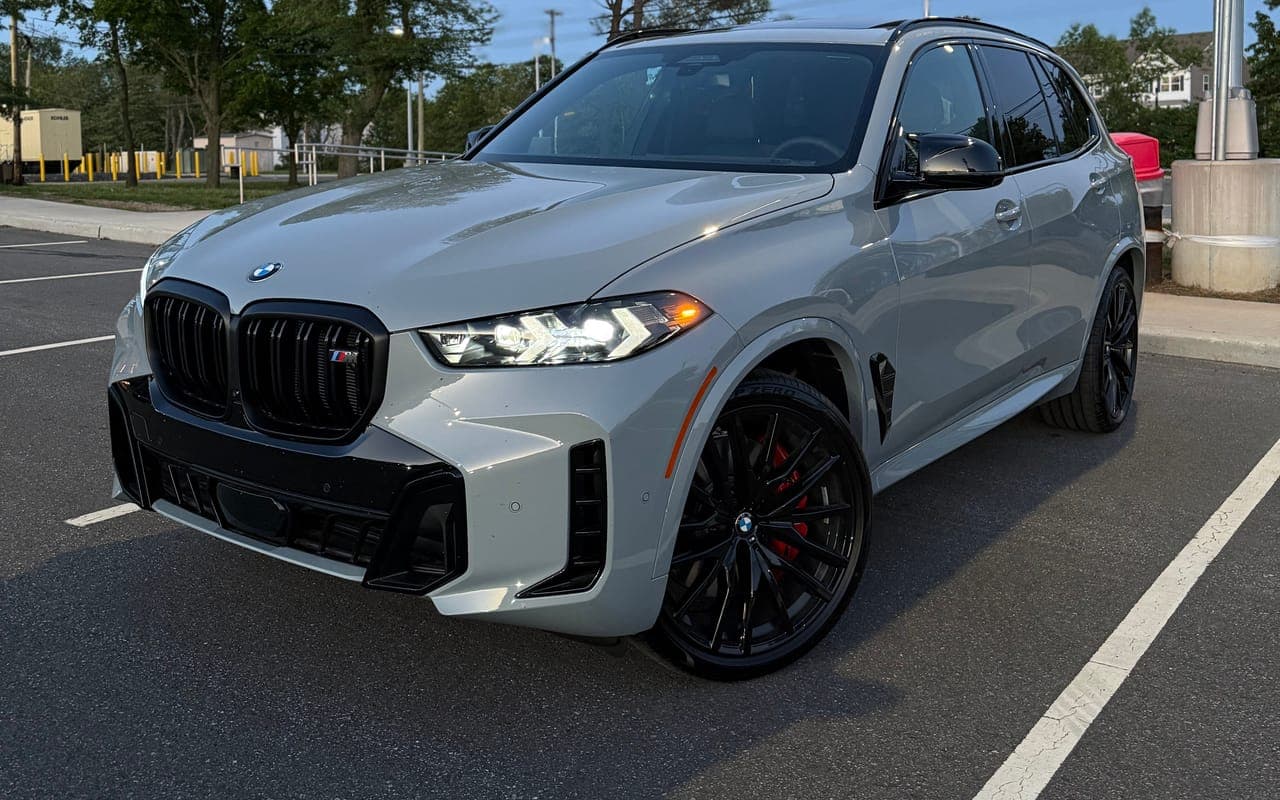 A grey BMW X5 M60i with black wheels parked at dusk
