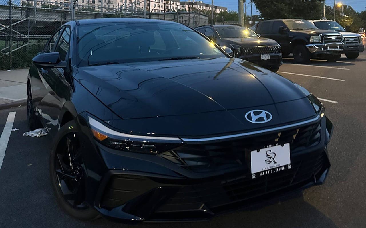 A black Hyundai Elantra in a parking lot at dusk, seen from the front