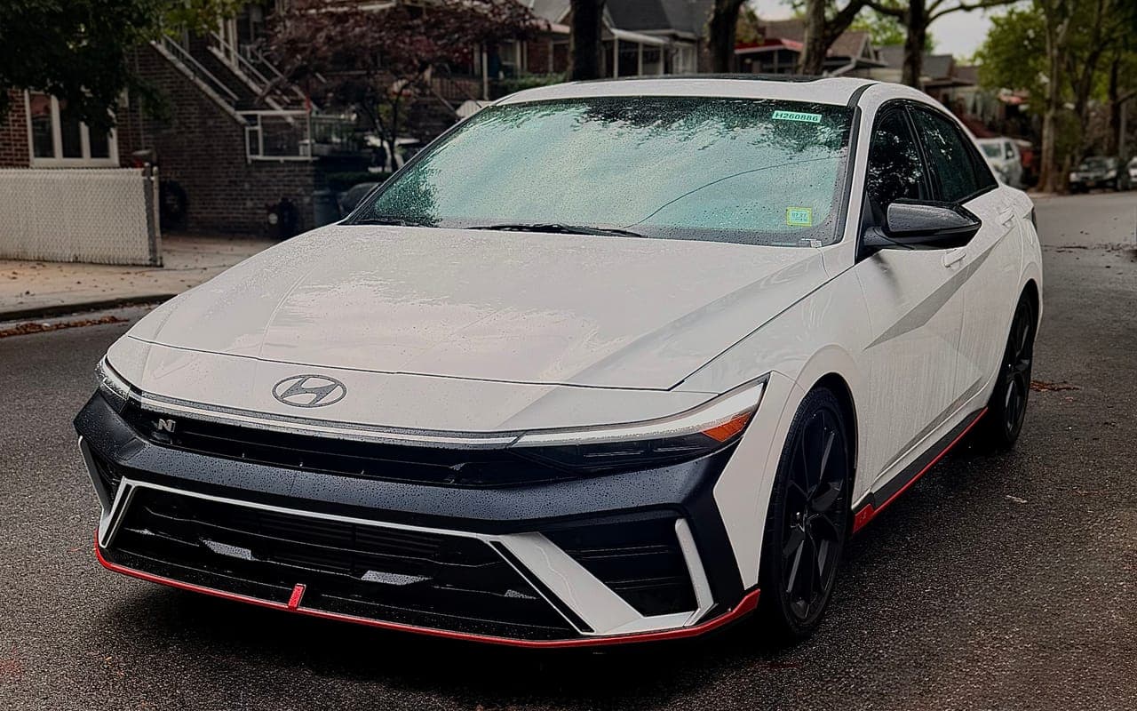 A white Hyundai Elantra N on a wet residential street