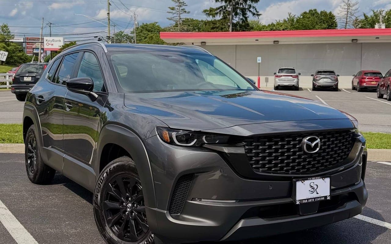 A grey Mazda CX-50 Hybrid with black wheels in a parking lot, seen from the front