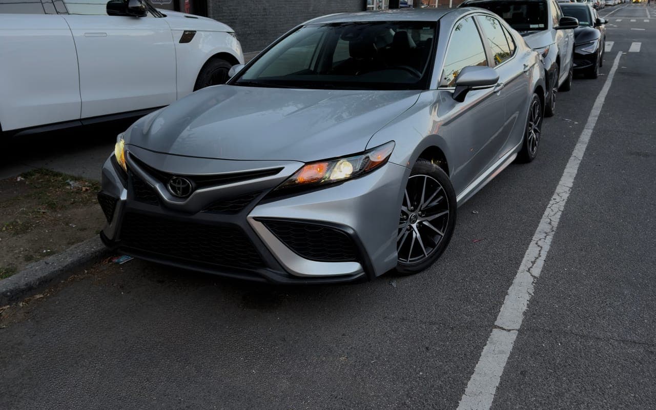 A silver Toyota Camry SE parked on a city street at dusk