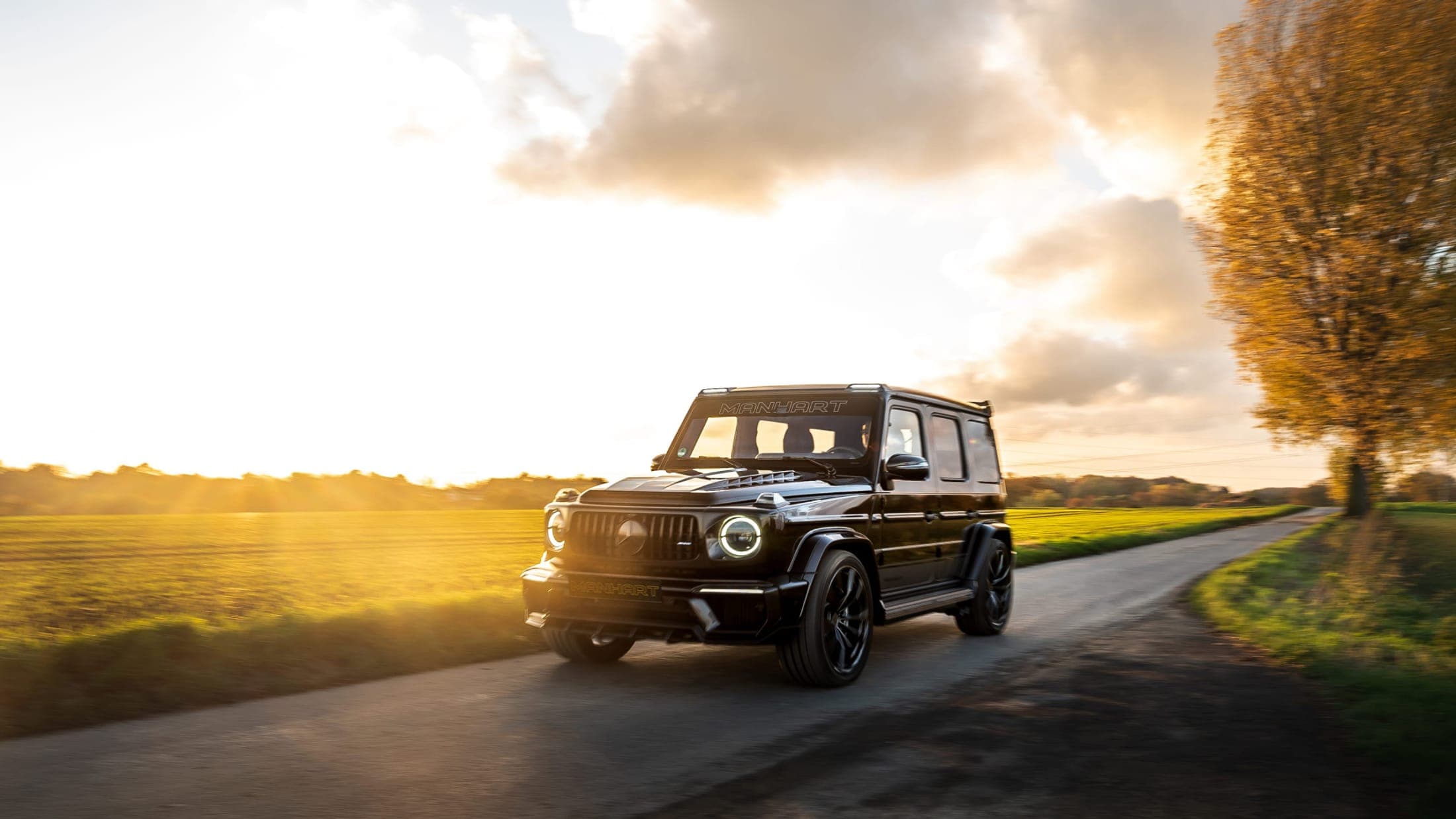 A Mercedes-AMG G-Class travelling a country road at sunset
